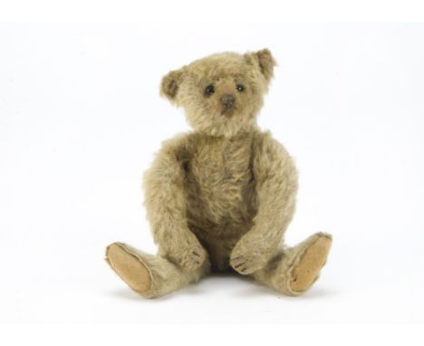 A small Steiff teddy bear, circa 1910, with blonde mohair, black boot button eyes, pronounced clipped muzzle, black stitched 