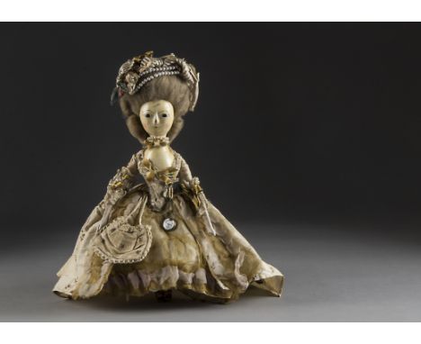 A fine small English turned and carved painted 18th century wooden doll in full formal evening dress, with inset dark glass e