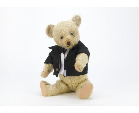 A 1930s British teddy bear, with light golden mohair, replaced glass eyes, black stitched nose, mouth and claws, swivel head,