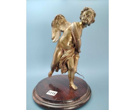 A bronze figure of Cupid reaching for an arrow from his quiver, with a wood stand.   H 28cms