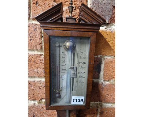 A mahogany stick barometer with a broken arch pediment above the silvered dial flanked by an alcohol Fahrenheit thermometer