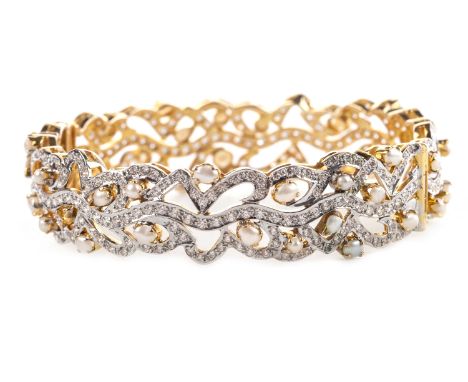 WHITE GEM SET BANGLE, of circular form, pierced and set with white gems and split pearls, 16mm at widest point, marked 750, 3