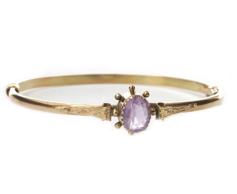 EARLY TWENTIETH CENTURY PURPLE GEM SET BANGLE, with a central oval faceted purple gem 9mm long in a collet setting, with appl