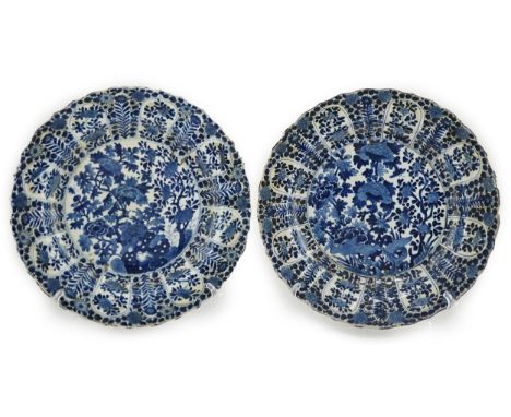 A pair of Chinese blue and white chargers, Kangxi period (1662-1722), each painted to the centre with flowering shrubs and ro