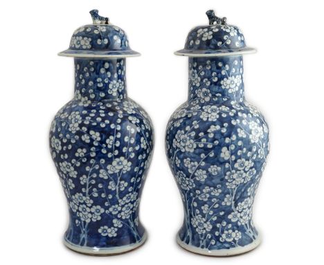 A pair of large Chinese blue and white ‘prunus’ baluster vases and covers, 19th century, each cylindrical neck surmounted by 