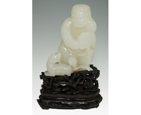 A fine Chinese white jade group of a bearded foreigner, 18th century, the man holding a brocaded ball with a lion-dog by his 