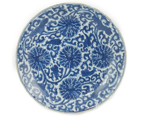 A large Chinese blue and white ‘lotus’ dish, Kangxi period, painted with five lotus flowers, scrolling tendrils and leaves, t