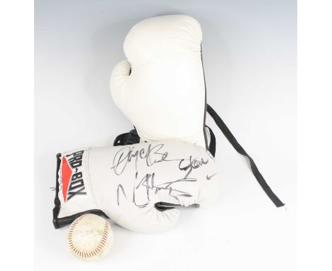 A pair of Pro-Box white leather boxing gloves, the left glove bearing the signatures of Nigel Benn, Steve Collins and Nicola 