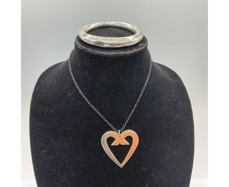This pair includes a faceted-style bracelet and an Adis-marked stylized heart pendant, presented on a braided black cord neck