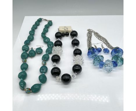 A lot featuring three vintage costume jewelry sets, including three necklaces with accompanying earrings. The black and clear
