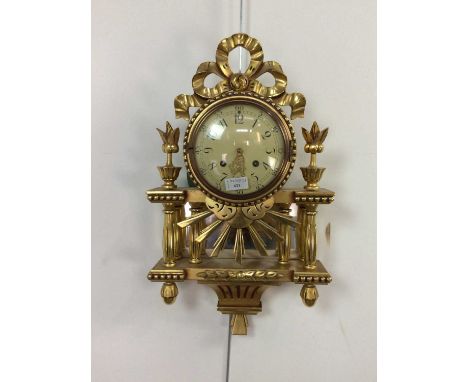 20TH CENTURY GILT WALL CLOCK OF FRENCH DESIGN,with ribbon surmount, the circular dial set with Arabic numerals, the case with