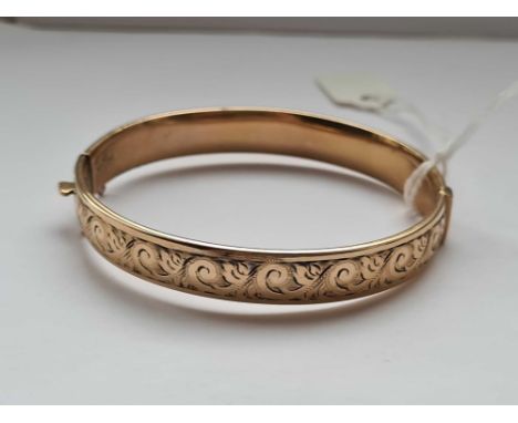 A scroll engraved rolled gold bangle