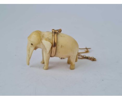 A vintage carved elephant with high carat gold belly band on gold safety chain
