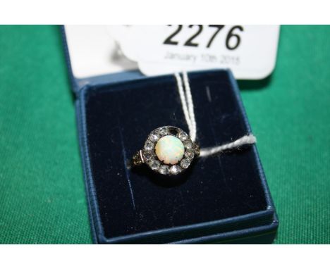 An early unmarked gold, silver set Diamond and opal Ring, having central round opal surrounded by eleven rose cut diamonds (o