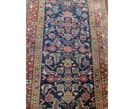A Persian runner, with meander foliage ornament on midnight blue ground in floral borders, 288 x 110cm