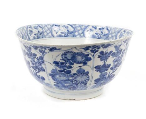 A large Chinese blue and white bowl, Kangxi period, painted with panels of flowers issuing from rockwork, the inside of the r