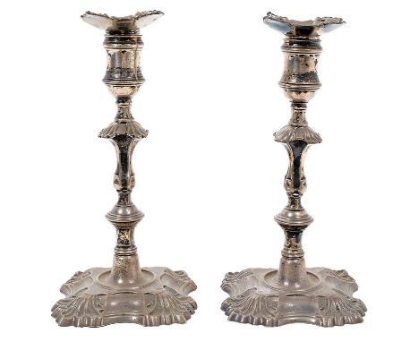 Pair of George II cast silver candlesticks with knopped stems and cotton reel candle holders, on stepped shell and scroll bas