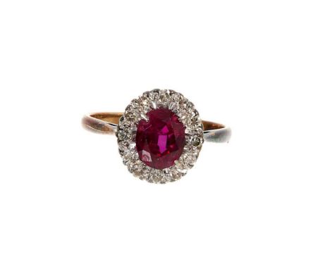 Ruby and diamond cluster ring with an oval mixed cut ruby measuring approximately 6.8mm x 5.5mm surrounded by a border of twe