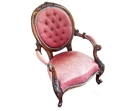Victorian carved walnut and button upholstered open armchair, with pink upholstery, raised on castors