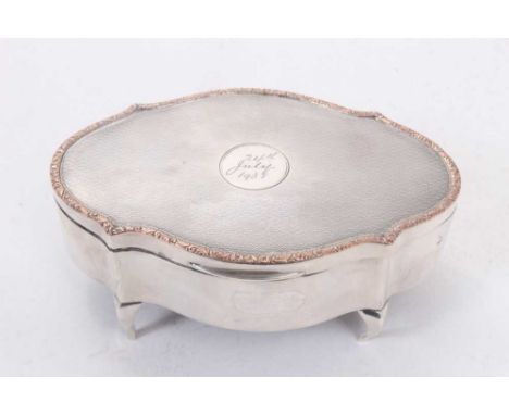 George V silver jewellery box of shaped oval form with engine turned decoration, engraved date to central cartouche, hinged c