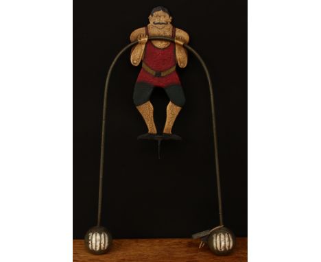 Folk Art - a novelty balance toy, in the form of a Circus strongman, he stands with his arms towards his chest holding a bar 