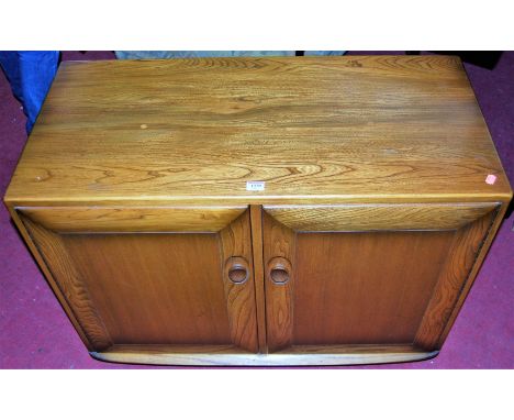 An Ercol mid-elm low double door side cupboard, w.91cm