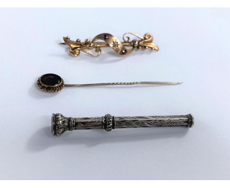 An Edwardian bar brooch with entwined filigree decoration, set 2 small rubies and a diamond; a stick pin set amethyst coloure