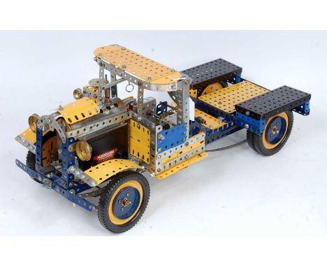 A Meccano live steam powered model of a road transport lorry constructed from blue, yellow and silver components, fitted with