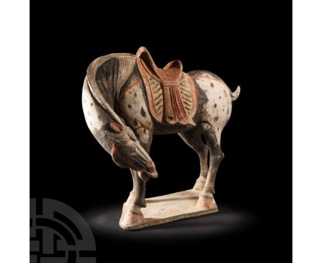 Tang Dynasty, 618-907 A.D. Modelled in the round, standing with head and neck bent around to the left side of the body, weari