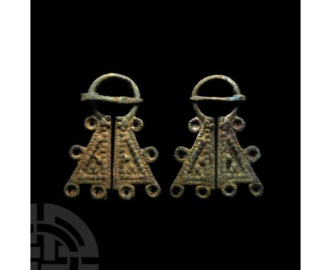 Circa 12th century A.D. Comprising a round-section hoop and two trapezoidal plate finials each with a geometric design of gra