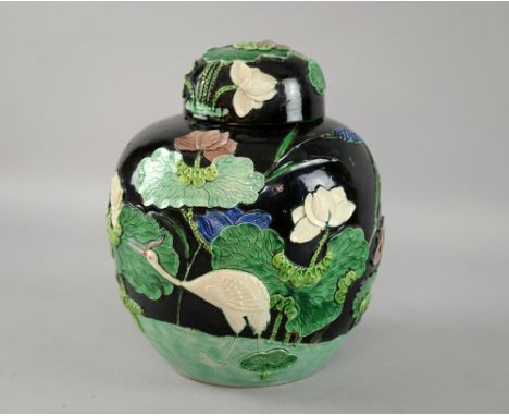 Chinese famille verte ginger jar and cover, the black ground with applied decoration of water lilies and water fowl, raised s