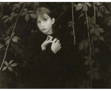 John "Jock" Sturges (American, b. 1947). Gelatin silver print photograph depicting a young girl in black surrounded by leaves