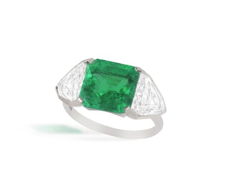 LANGI: AN IMPRESSIVE EMERALD AND DIAMOND RINGCentring an octagonal step-cut emerald weighing 4.36cts within a four-claw setti