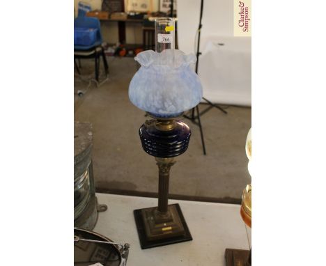 A brass Corinthian column oil lamp with blue glass reservoir and mottled shade 