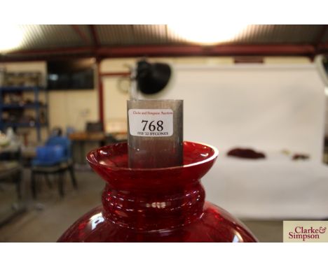 A ruby glass table oil lamp hung with prism drops and mounted on a brass cherub column (one drop missing)