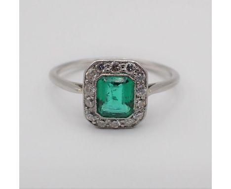 An Art Deco Emerald and Diamond Cluster Ring millegrain-set step-cut emerald within a frame of brilliant and eight-cut diamon