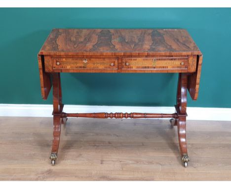 A Regency style rosewood veneered and brass inlaid Sofa Table on lyre shaped end supports united by turned stretcher and term