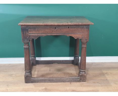 An early 17th Century oak Rent Table with hinged lid above shaped apron raised on barrel turned supports united by surroundin