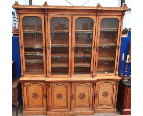 A late 19th Century light oak aesthetic movement Breakfront Bookcase, with castellated cornice above four glazed doors enclos