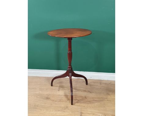 An early 19th Century mahogany tilt top Table with oval top on slender baluster column and reeded downswept supports 