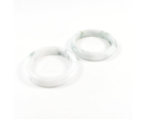 A pair of jadeite bangle bracelets. The first solid bangle of predominantly white &amp; pale green &amp; the second of pastel