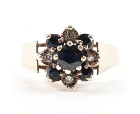 A hallmarked 9ct yellow gold, sapphire &amp; diamond cluster ring. The ring having a central round cut sapphire surrounded by