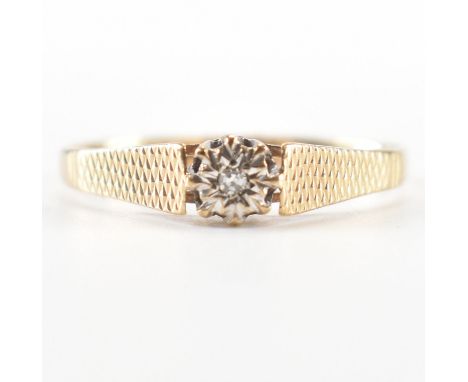 A hallmarked 9ct gold and diamond ring. The ring being illusion set with a round cut diamond with textured shoulders. Hallmar