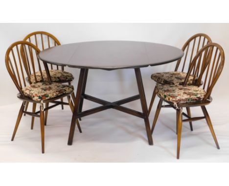 An Ercol dark elm oval drop leaf kitchen table, with X shaped support, and four stick back chairs on turned legs, the table 1