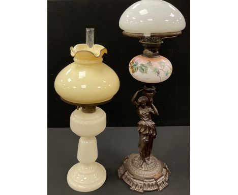 A cast iron figural oil lamp, moulded patterned base, with figure holding painted milk glass shade, 78cm high; A late 19th ce