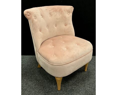 A contemporary pastel pink velvet upholstered, button back bedroom chair.