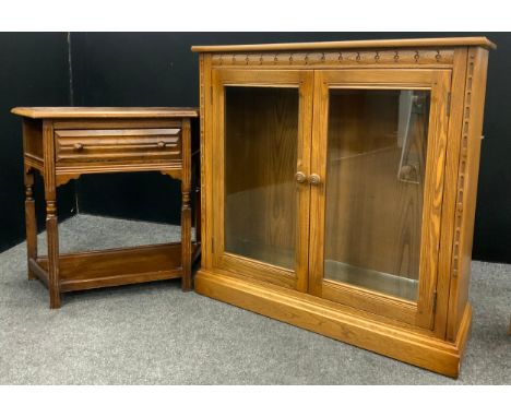 An Ercol side cabinet, slightly oversailing top, with carved frieze above two large glass panel doors; an oak side table, sin