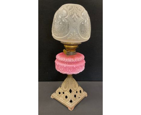 A Victorian pink and white milk glass and cast iron oil lamp, moulded floral reservoir, frosted and moulded shade, cast iron 