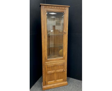 An Ercol floor standing corner cupboard - carved to frieze, large glass panel door enclosing three adjustable shaped glass sh