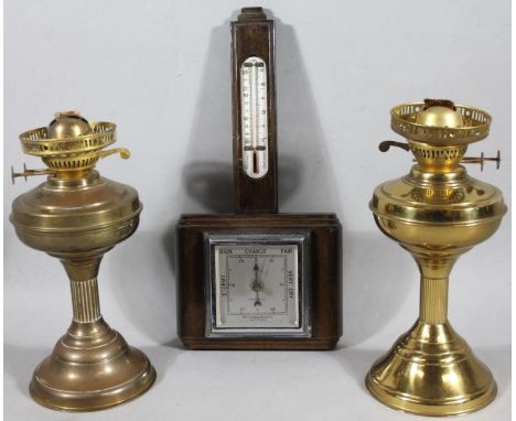 Two early 20thC brass oil lamp bases, and a stained beech barometer and thermometer, 46cm high. (3)